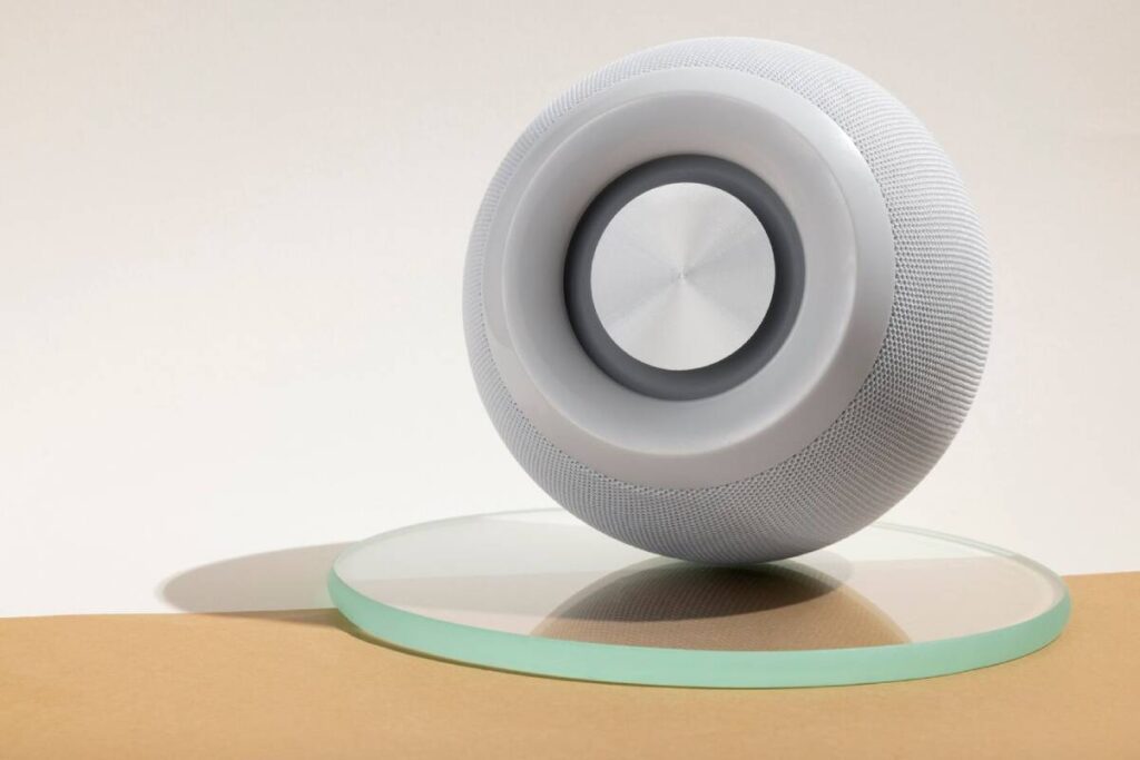 A white textured circular object on a glass disc, casting a soft shadow on a light brown surface.