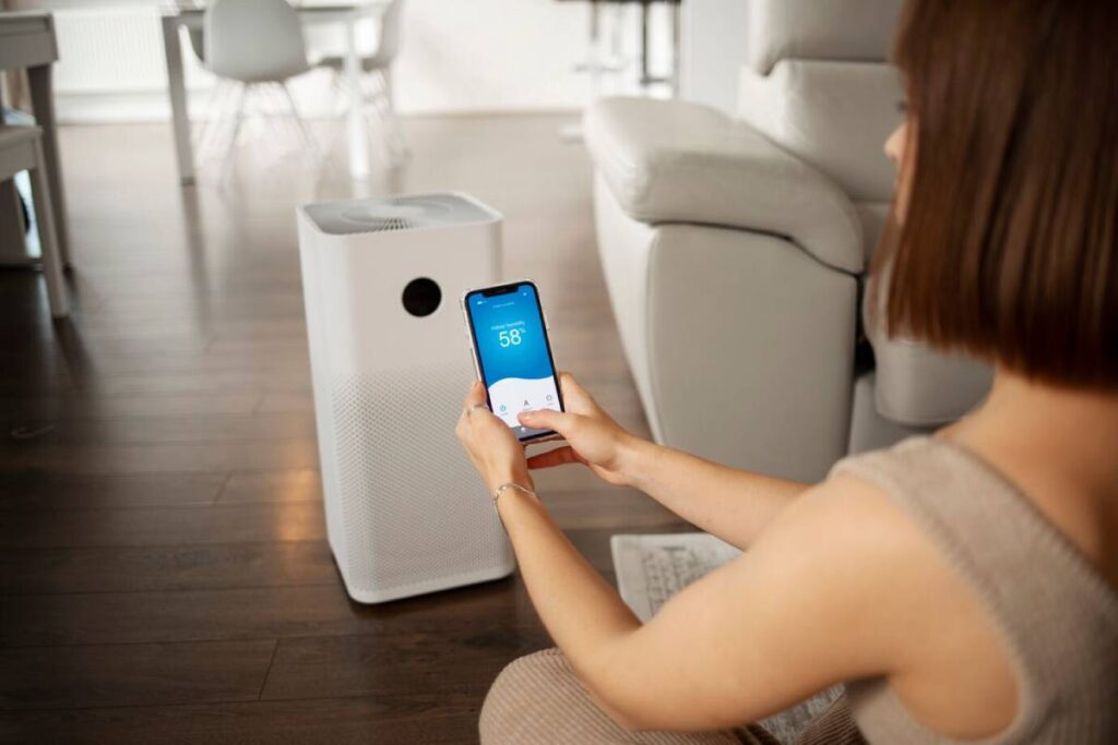 Woman using a smartphone to control a white air purifier in a modern home.