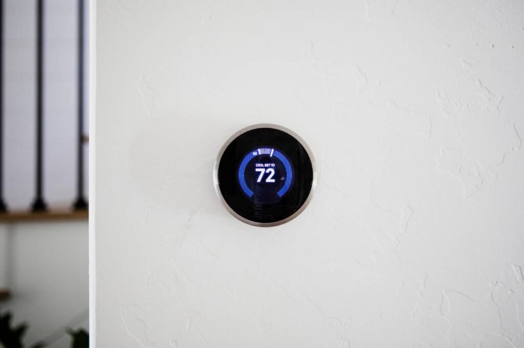 Smart thermostat mounted on a wall, displaying temperature settings and energy-saving features in a modern home environment.