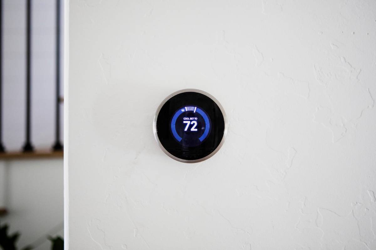 Smart thermostat mounted on a wall, displaying temperature settings and energy-saving features in a modern home environment.