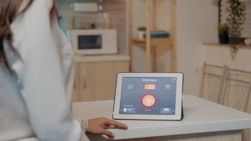 Woman using a smart home tablet to control kitchen appliances in a modern kitchen setting.