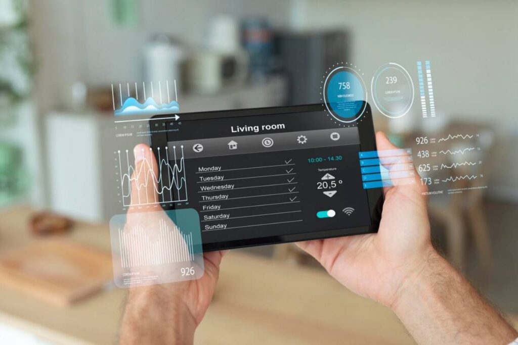 A person holding a transparent digital tablet displaying various environmental and statistical data for a living room.