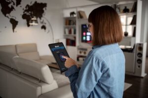 Woman using a smart home device to control music in a modern living room.