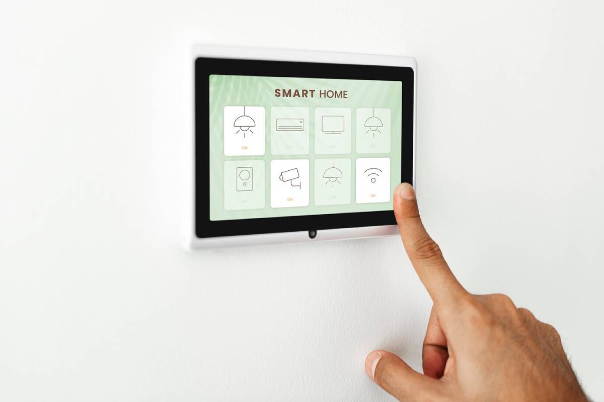 Person using a touchscreen panel for smart home control mounted on a wall.