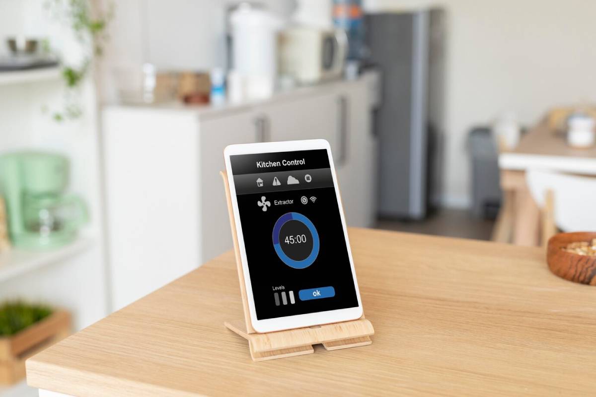  A modern, tablet-like kitchen control device on a wooden stand showing cooking time, set in a tidy kitchen environment.