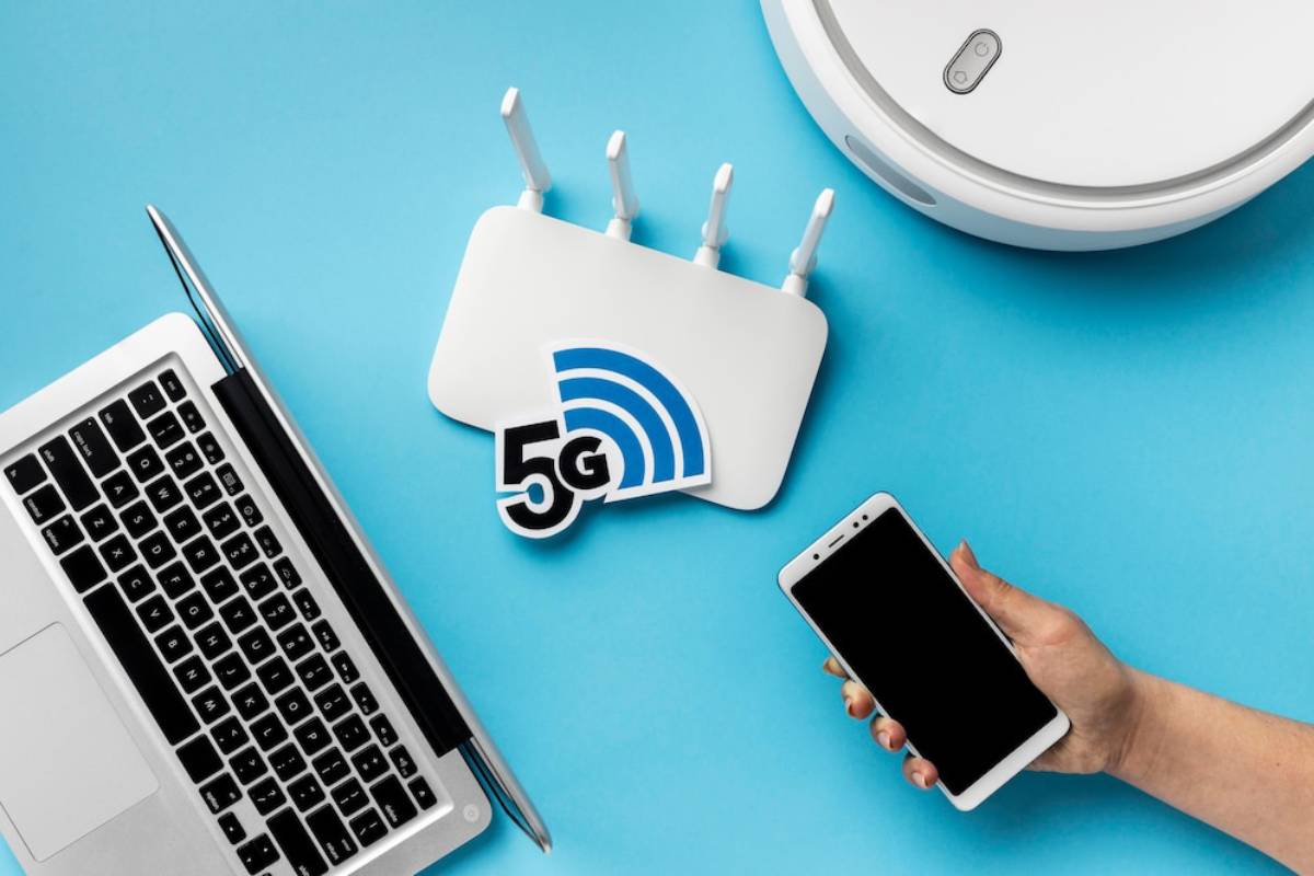 A laptop, 5G router, smartphone, and robotic vacuum cleaner on a blue background, illustrating modern wireless technology. 