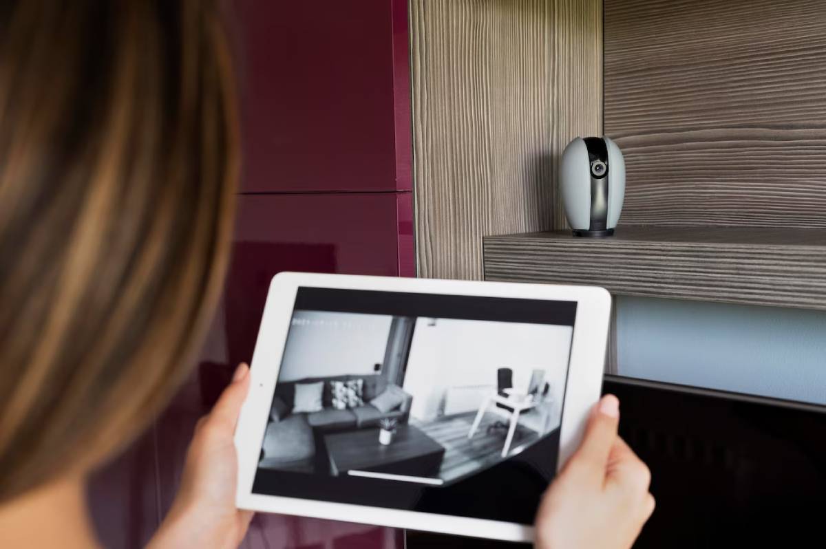 Woman monitoring her living room using a security camera app on a tablet.