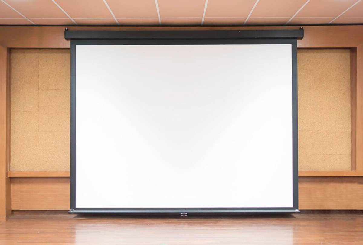  Large, empty projection screen in a room with wooden floor and cork wall.