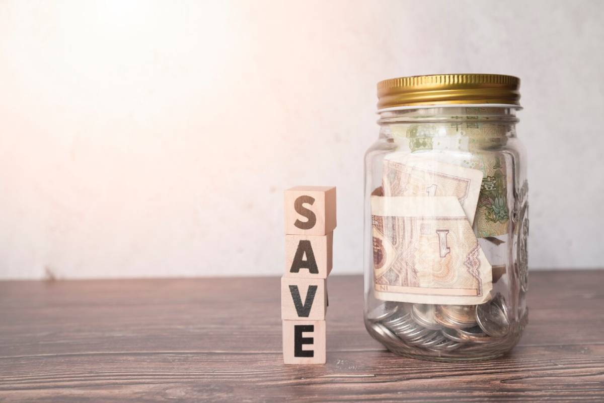  Wooden blocks and a jar on a wooden table symbolize saving money and financial planning.
 