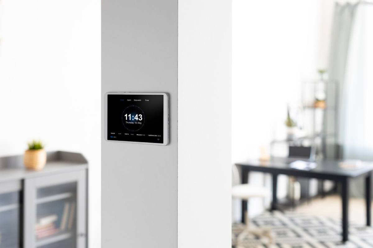 A digital wall-mounted clock displaying the time and date in a modern living room. 