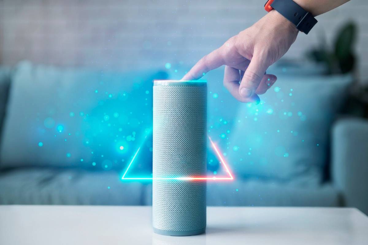  Person activating a smart speaker which projects glowing, colourful light effects in a modern living room.